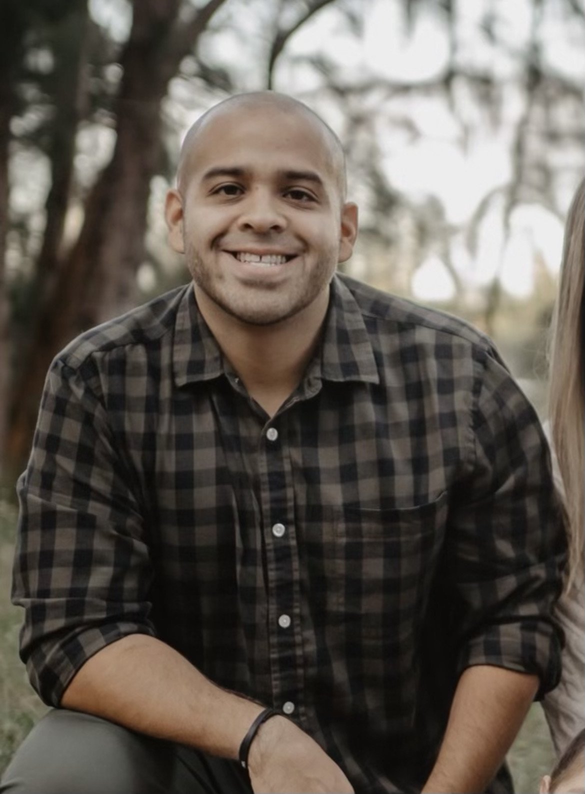 A young man in a plaid shirt smiling outdoors at a Take Stock in Children of Broward event